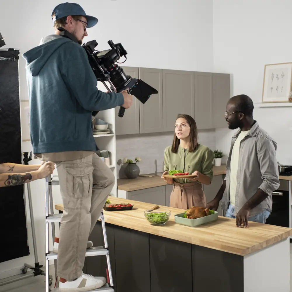 A filming crew records a cooking video with two chefs in a kitchen.
