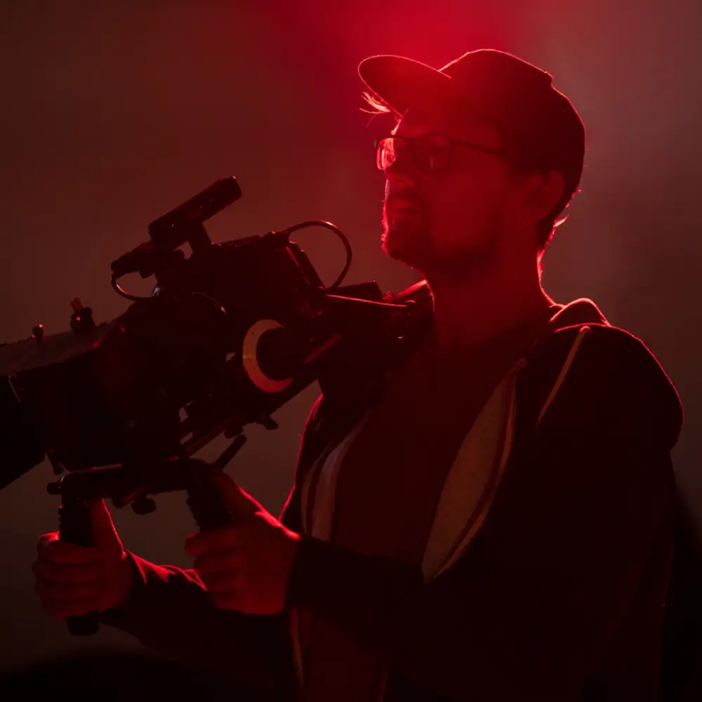 A person filming with a professional camera in red lighting.